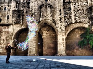 homme faisant des bulles d'eau devant un bâtiment du quartier gothique de barcelone