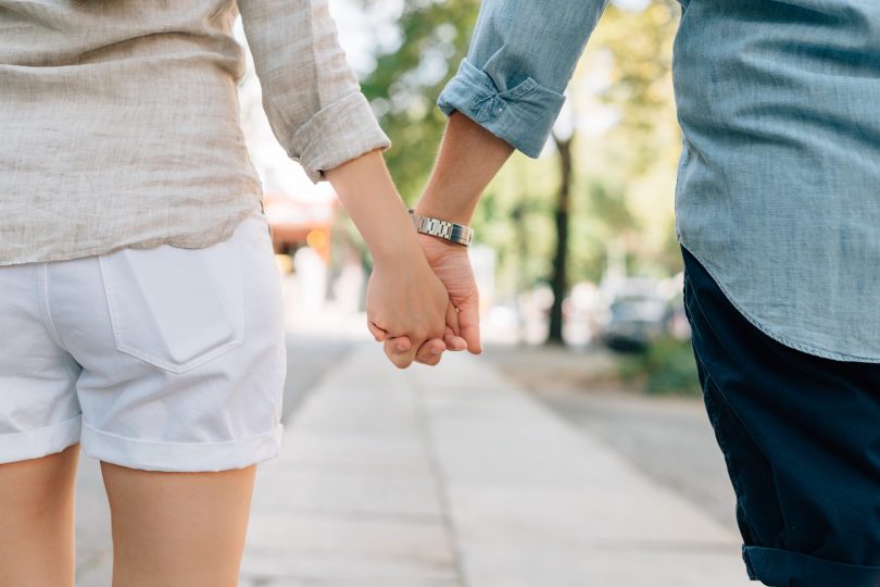 homme et femme se tenant la main dans la rue