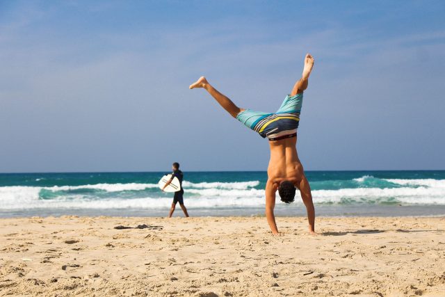 homme faisant de l'acrobatie sur la plage