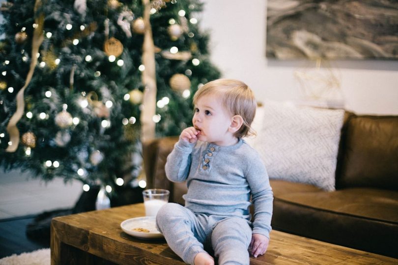 Niño comiendo sobre la mesa con árbol de navidad de fondo