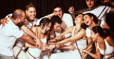 groupe mixte habillé en blanc riant et criant autour d'une corde