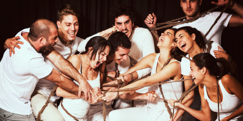groupe mixte habillé en blanc riant et criant autour d'une corde