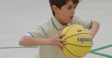 garçon en polo jouant avec un ballon de basket