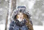 femme avec un manteau d'hiver soufflant sous la neige