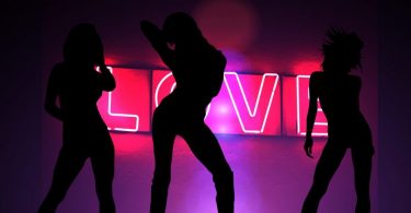 trois silhouettes de femme devant un neon rose love
