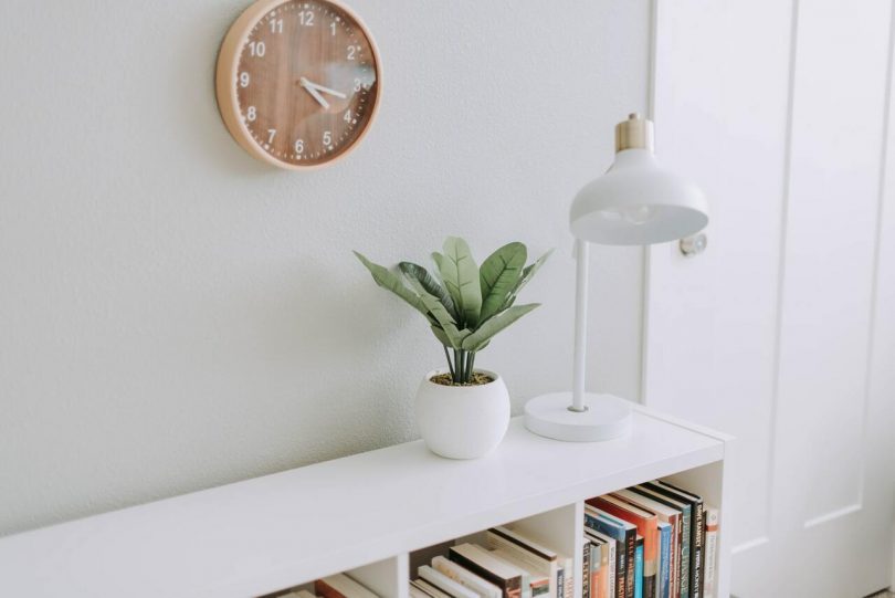 Meuble blanc et horloge en bois sur mur blanc