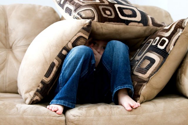 enfant caché sous des coussins sur un canapé
